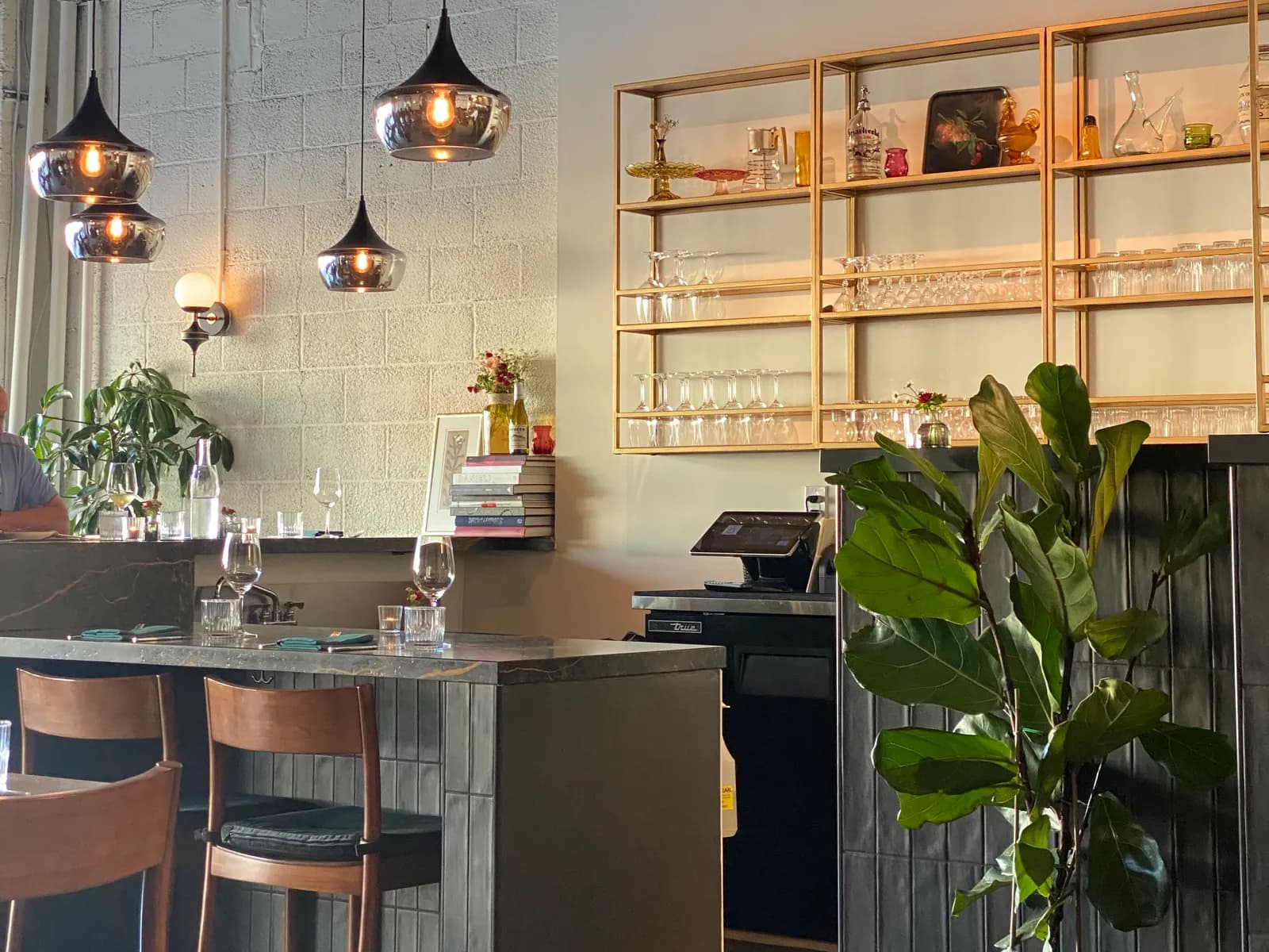Inside a Foothills restaurant, with pendant lights over the bar and gold shelves of glassware