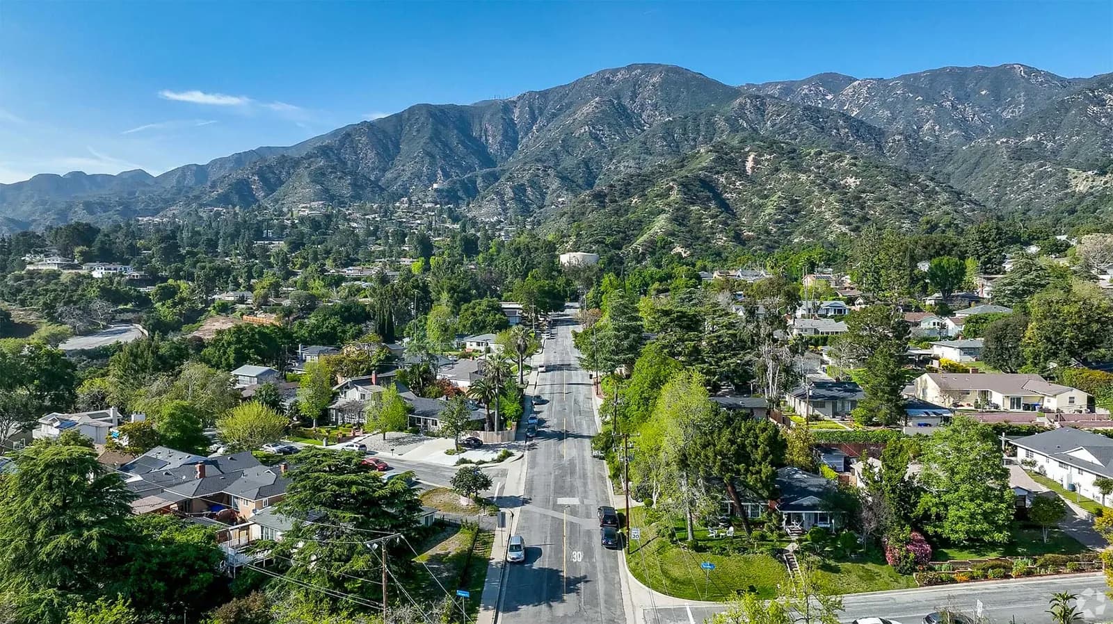 Aerial view up a tree-lined La Crescenta street toward the San Gabriel Mountains